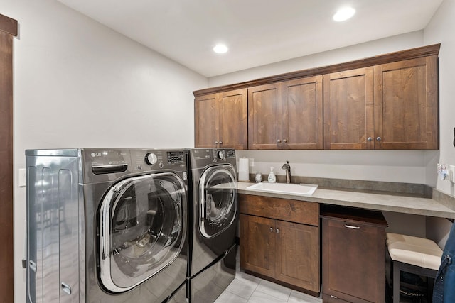 washroom with cabinets, light tile patterned floors, independent washer and dryer, and sink