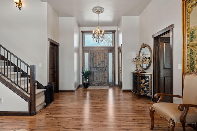 entryway with a high ceiling, dark wood-type flooring, and an inviting chandelier