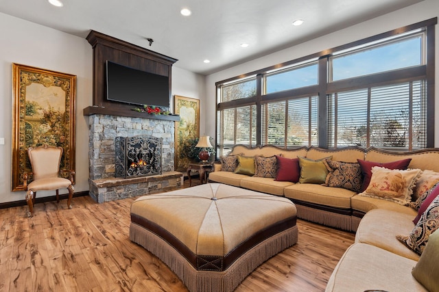 living room featuring light hardwood / wood-style flooring and a stone fireplace