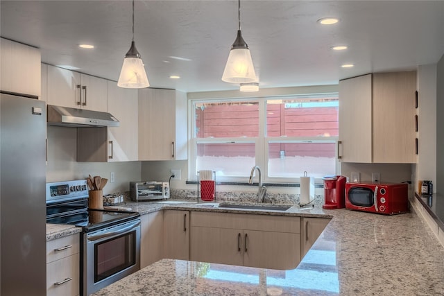 kitchen featuring light stone countertops, stainless steel appliances, light brown cabinetry, sink, and hanging light fixtures