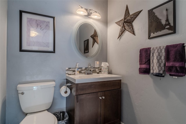 bathroom with toilet, vanity, and decorative backsplash