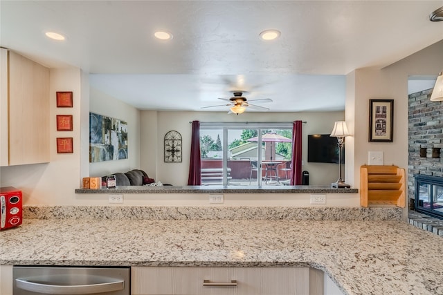 kitchen with a brick fireplace, light stone counters, and ceiling fan