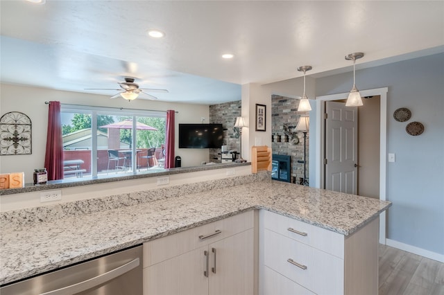 kitchen featuring white cabinetry, a fireplace, dishwasher, wood-type flooring, and light stone countertops