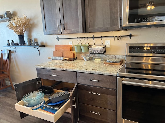 kitchen featuring stainless steel appliances, dark hardwood / wood-style floors, dark brown cabinetry, and light stone countertops