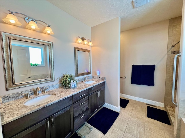 bathroom with a textured ceiling, tile patterned flooring, walk in shower, and vanity