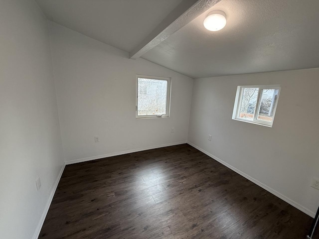 empty room featuring dark wood-type flooring, a textured ceiling, and lofted ceiling with beams