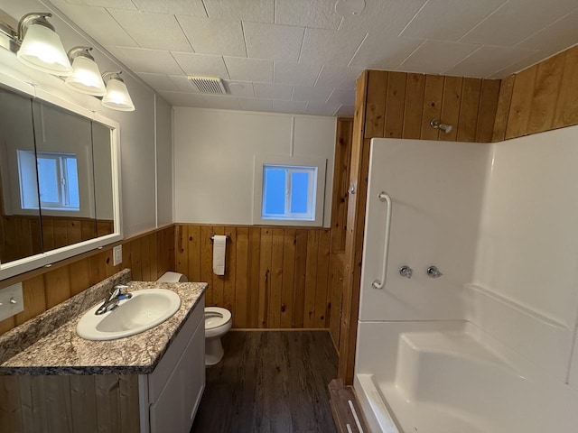 bathroom featuring wooden walls, toilet, hardwood / wood-style floors, and vanity