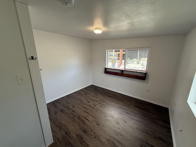 unfurnished room with dark wood-type flooring and a textured ceiling