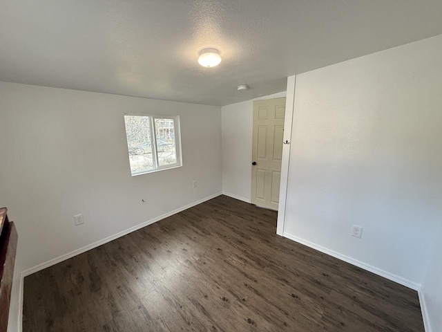 spare room featuring dark hardwood / wood-style floors and a textured ceiling