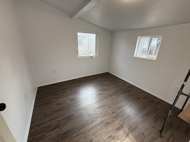 empty room featuring lofted ceiling with beams and dark hardwood / wood-style floors