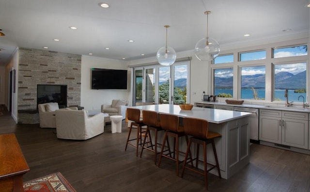 kitchen with a center island, sink, hanging light fixtures, dark hardwood / wood-style floors, and a breakfast bar