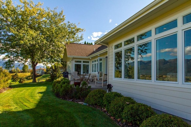 view of side of home featuring a lawn and a patio