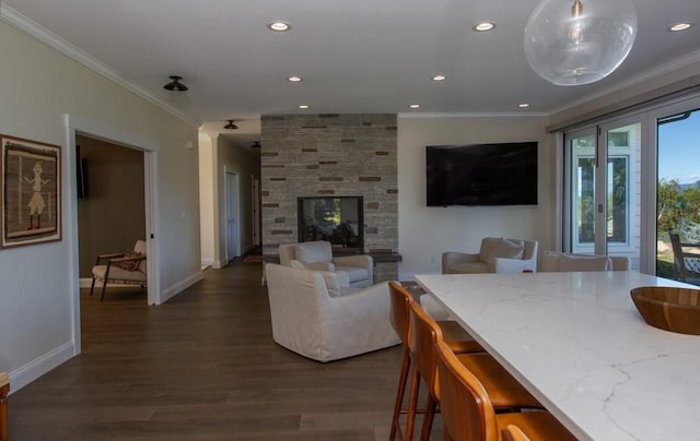 living room featuring dark hardwood / wood-style flooring, crown molding, and a stone fireplace