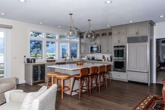 kitchen with a breakfast bar area, stainless steel appliances, gray cabinetry, and wine cooler