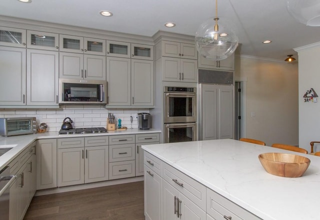 kitchen with stainless steel appliances, backsplash, dark hardwood / wood-style floors, hanging light fixtures, and ornamental molding