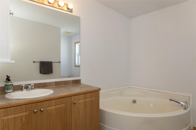 bathroom featuring toilet, vanity, and a bath