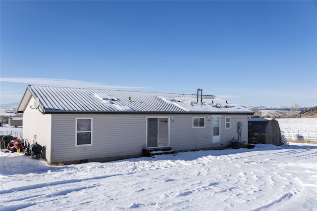 snow covered back of property featuring central AC unit