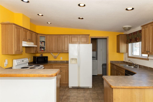 kitchen featuring kitchen peninsula, vaulted ceiling, black appliances, washer / clothes dryer, and sink