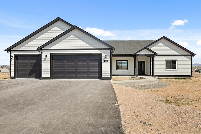 view of front facade with a garage, driveway, and roof with shingles