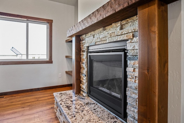 details with baseboards, wood finished floors, and a fireplace