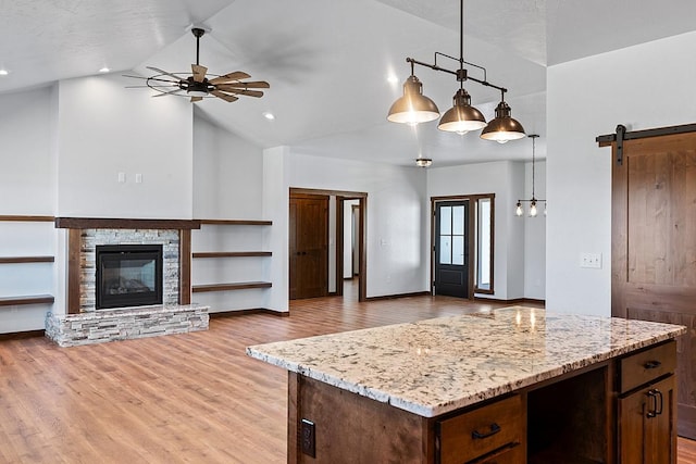 kitchen featuring ceiling fan, a barn door, open floor plan, light stone countertops, and high vaulted ceiling