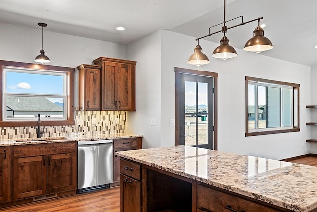 kitchen with light wood-style floors, dishwasher, decorative backsplash, and a sink