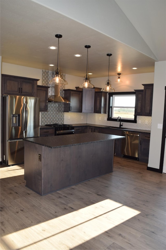 kitchen with dark brown cabinets, a center island, decorative backsplash, and appliances with stainless steel finishes