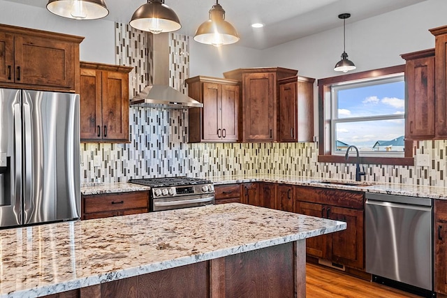 kitchen with light stone counters, decorative backsplash, appliances with stainless steel finishes, a sink, and light wood-type flooring