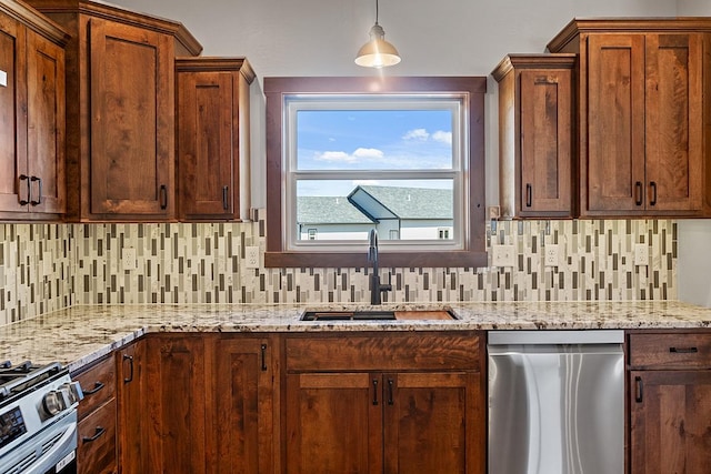 kitchen with light stone countertops, appliances with stainless steel finishes, backsplash, a sink, and pendant lighting