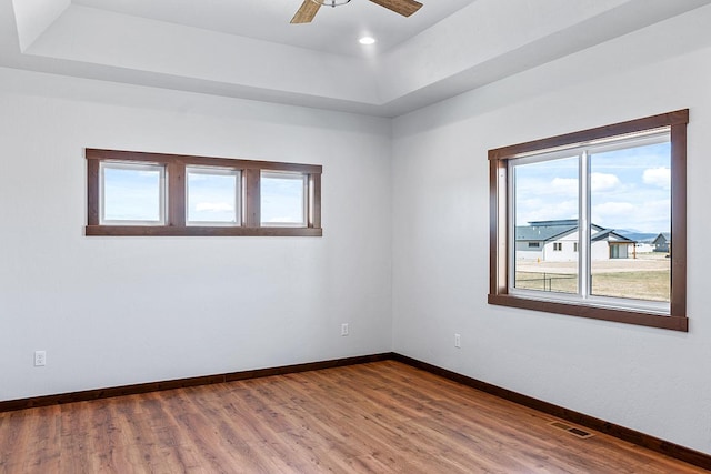 empty room with a raised ceiling, visible vents, and a healthy amount of sunlight