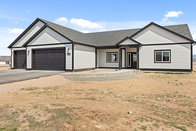 modern farmhouse featuring driveway, a shingled roof, and a garage