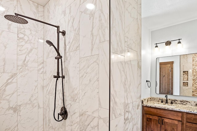 bathroom featuring tiled shower and vanity