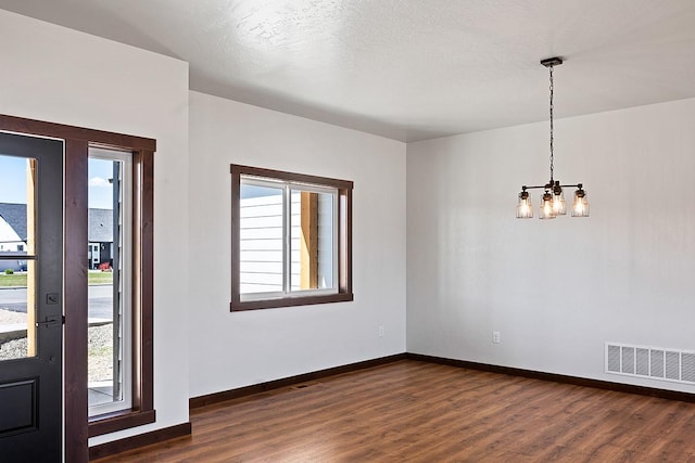 foyer entrance with a healthy amount of sunlight, visible vents, an inviting chandelier, and dark wood-style flooring