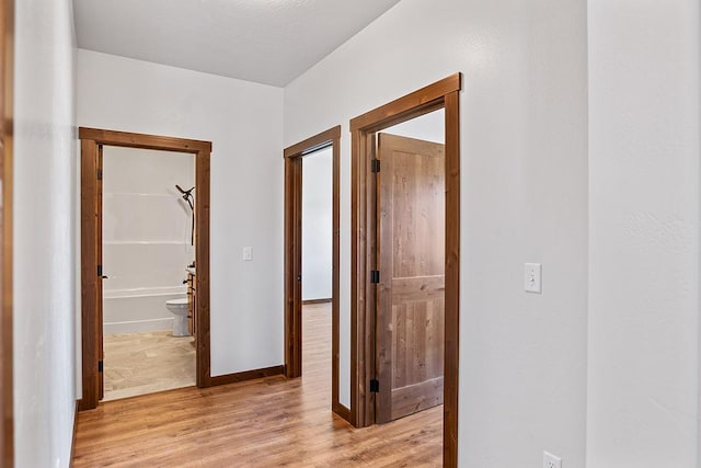 hall featuring baseboards and light wood-style floors