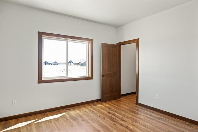 unfurnished room featuring visible vents, light wood-type flooring, and baseboards