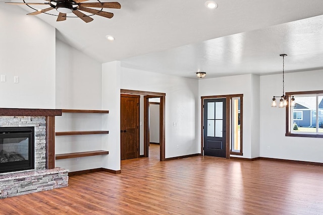unfurnished living room featuring wood finished floors, baseboards, recessed lighting, and ceiling fan with notable chandelier