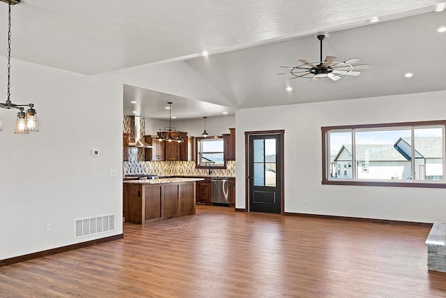 unfurnished living room with dark wood-style floors, visible vents, vaulted ceiling, baseboards, and ceiling fan with notable chandelier