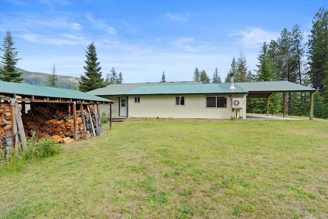 rear view of property with a mountain view, a yard, and a carport