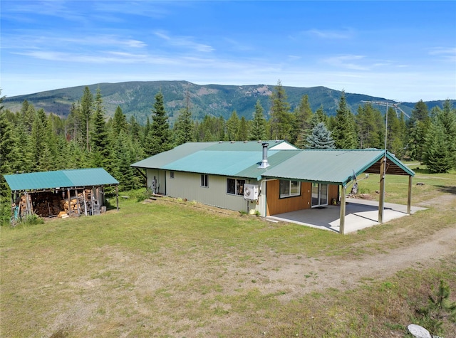 back of property with a patio area, a mountain view, and a yard