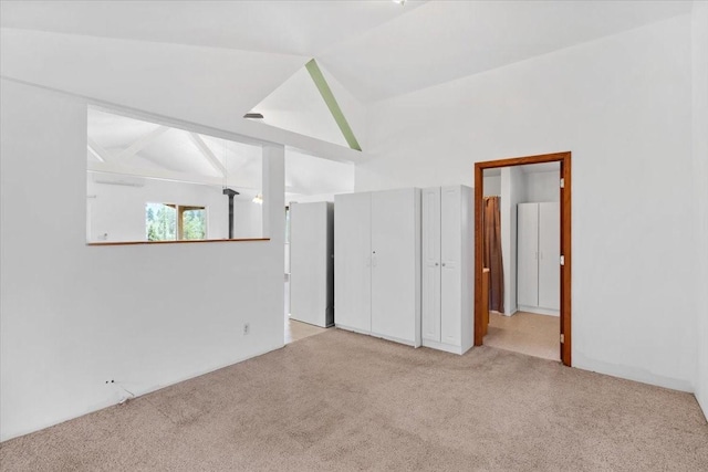 unfurnished bedroom featuring light carpet and lofted ceiling