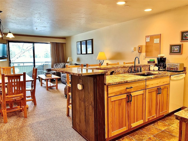 3898 Big Mountain Rd Unit 202, Whitefish, MT 59937 - kitchen featuring white dishwasher, a breakfast bar, a peninsula, brown cabinets, and recessed lighting