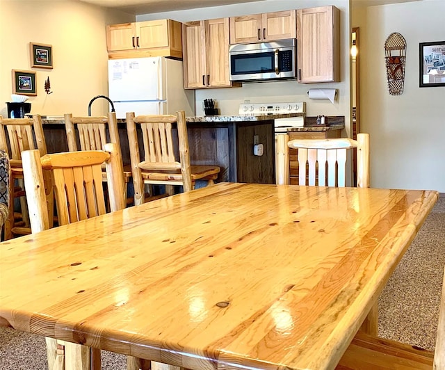 3898 Big Mountain Rd Unit 202, Whitefish, MT 59937 - kitchen with white appliances, light brown cabinetry, and a breakfast bar area