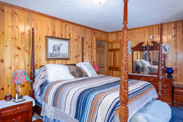 bedroom featuring a textured ceiling, crown molding, and wooden walls