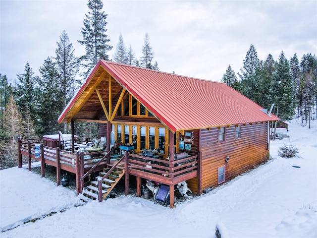 snow covered back of property with a deck