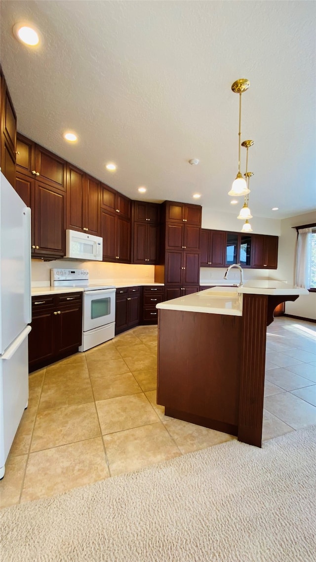 kitchen with an island with sink, white appliances, light tile patterned flooring, hanging light fixtures, and sink