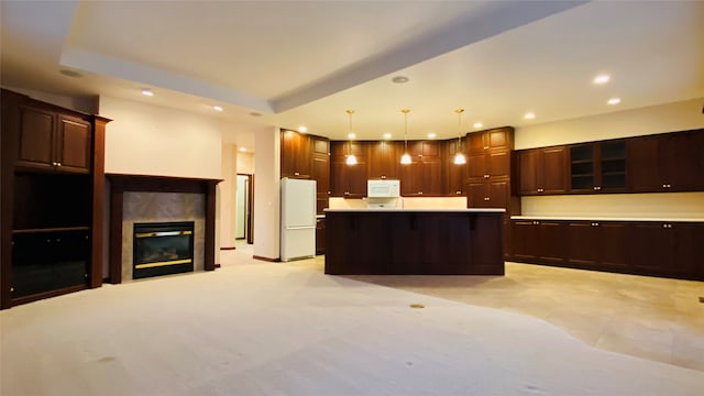 kitchen featuring white appliances, dark brown cabinetry, a center island, a fireplace, and hanging light fixtures