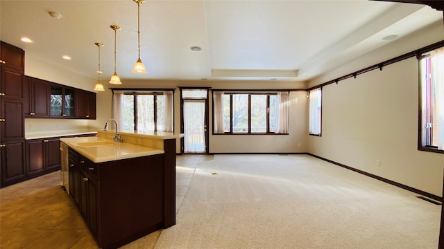 kitchen featuring a wealth of natural light, a kitchen island with sink, hanging light fixtures, and sink