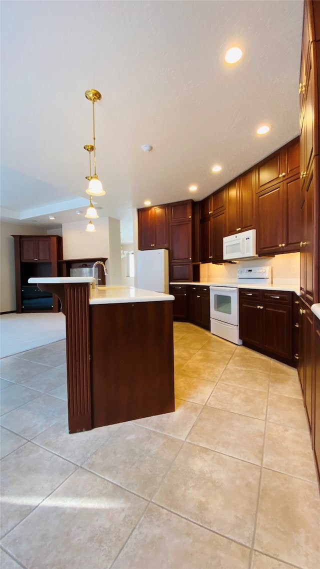 kitchen featuring pendant lighting, white appliances, a center island with sink, and a kitchen bar