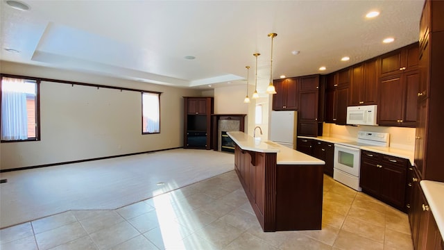 kitchen with pendant lighting, white appliances, a kitchen bar, light carpet, and a center island with sink