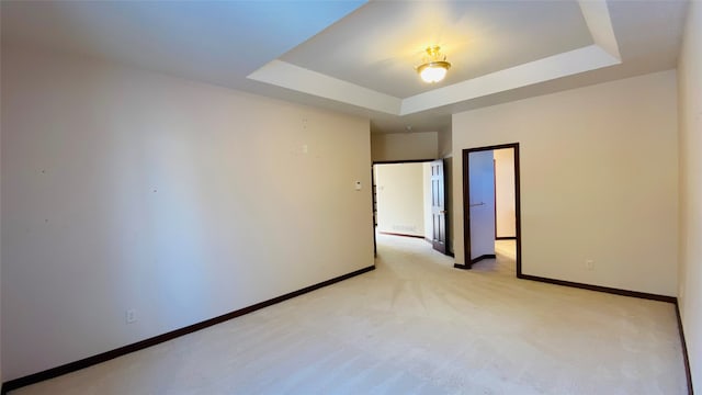 unfurnished room with a tray ceiling and light carpet